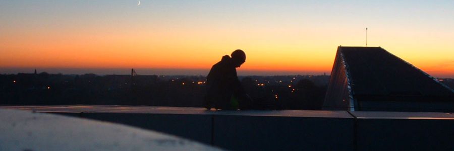 image formation où un technicien travail sur un toit au couché du soleil